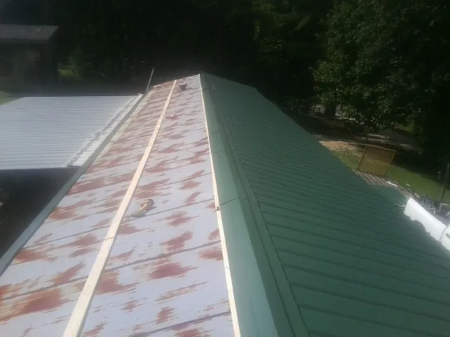 Old rusted panels beside newly installed green metal roofing — Wind Damage Roof Repair by Roofing Brothers in Rhododendron