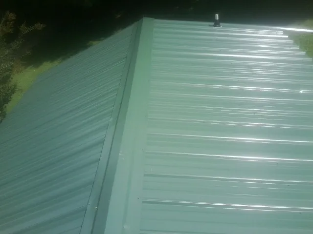 New green metal panels meeting at the ridge of a roof — Flat Roof Repair work by our crew in Rhododendron