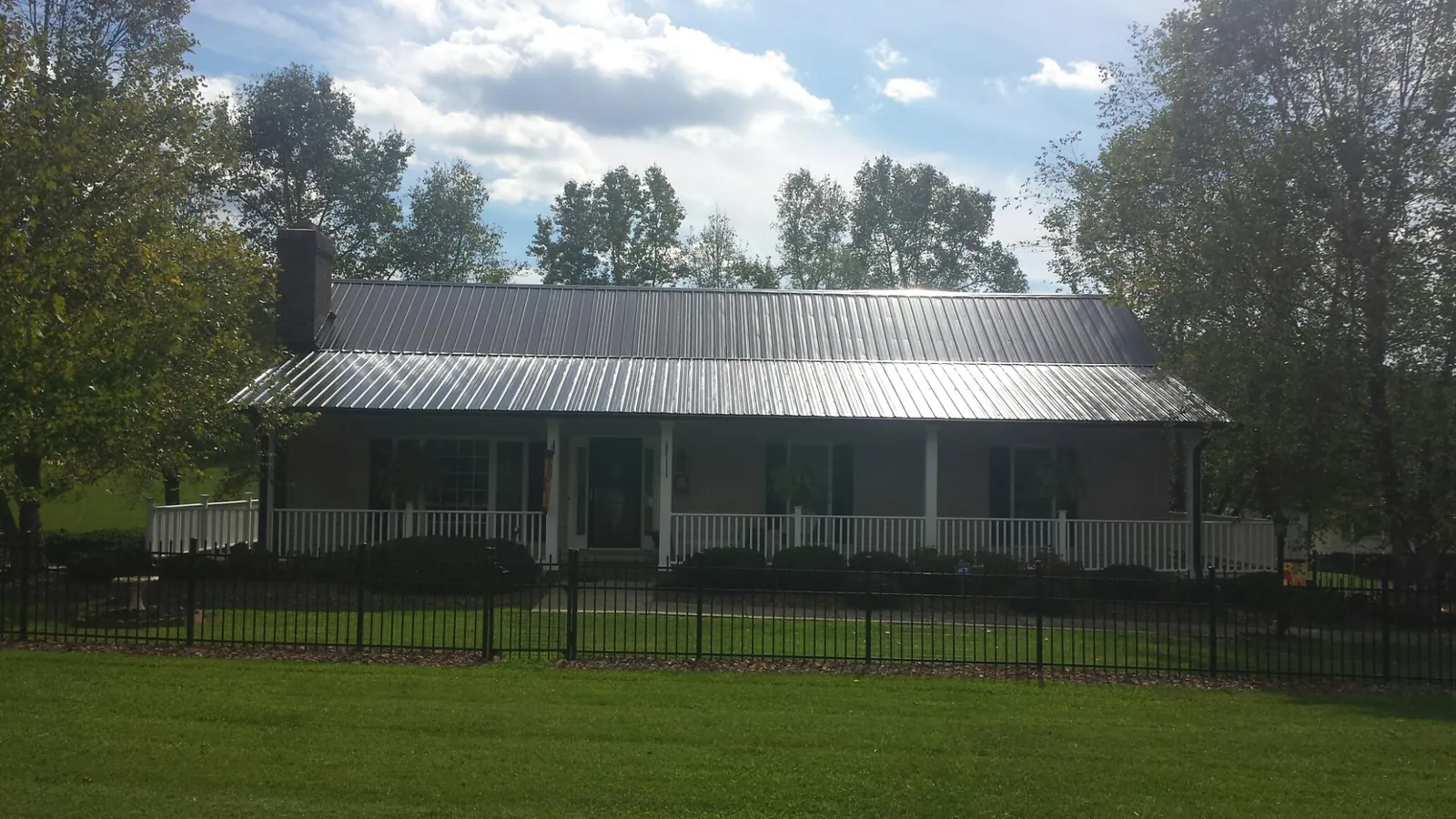Gray metal roof on a brick ranch with a full width front porch — Gutter Guard Installation work by our crew in Rhododendron