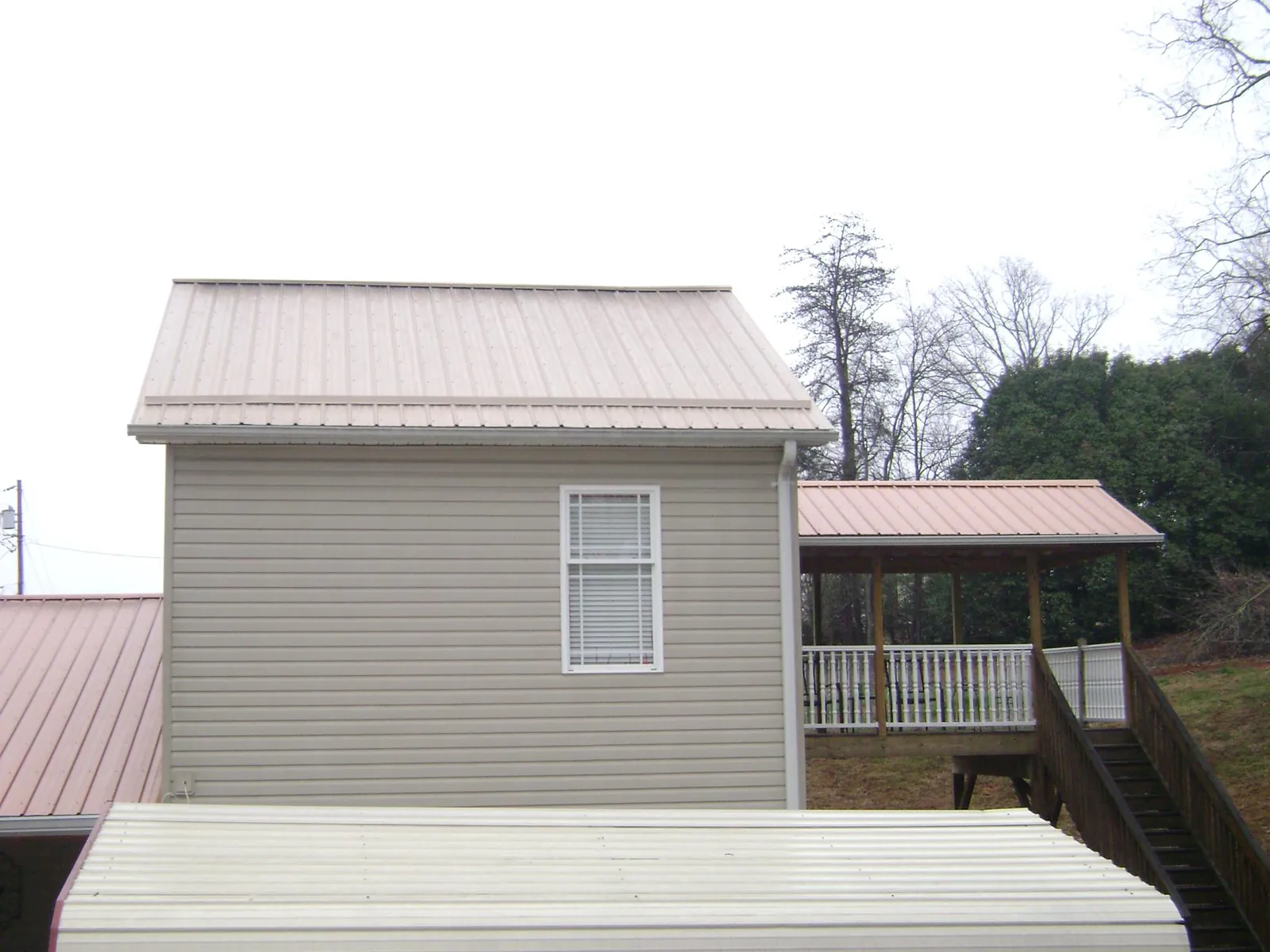 Tan metal roofs on a two story addition and attached porch, from a Roof Replacement job in Rhododendron