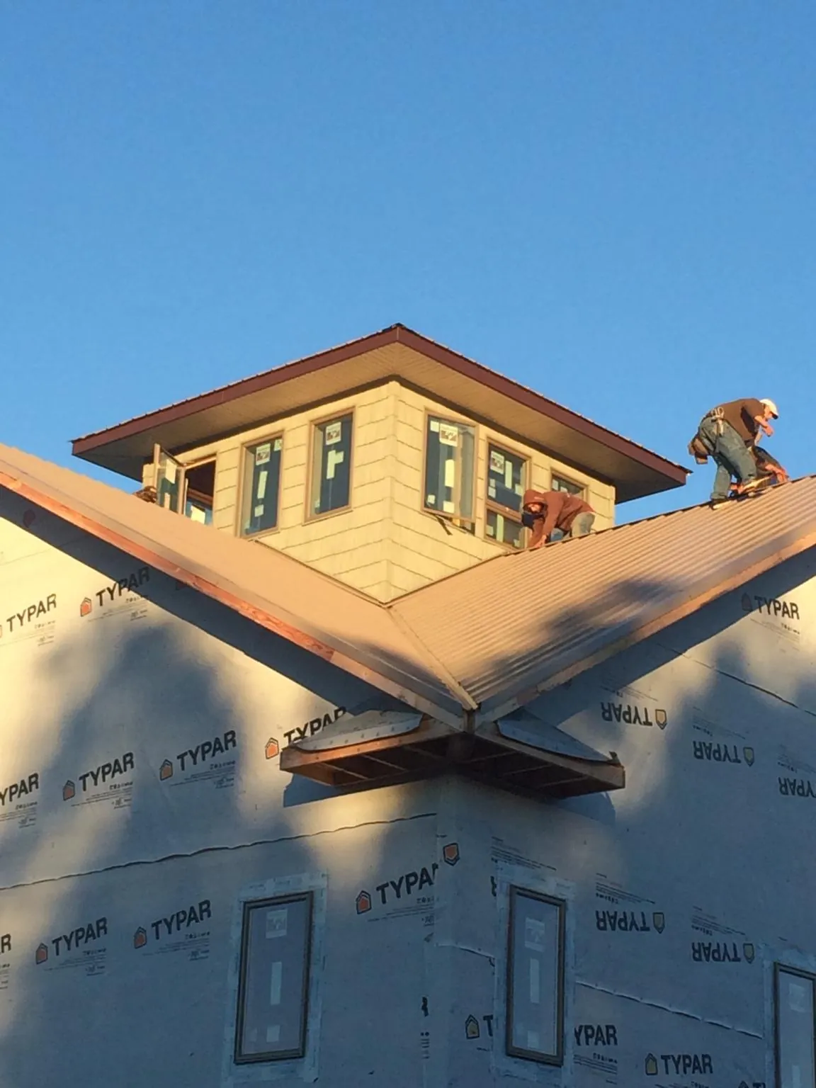 Roofers working around a rooftop cupola on a new metal roof at sunset — Roof Waterproofing in Rhododendron by Roofing Brothers